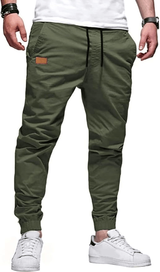 A person wearing olive green jogger pants with an elastic waistband and drawstring, complemented by white sneakers.