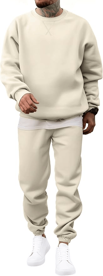 A person wearing a light beige sweatshirt and matching sweatpants, standing casually in white sneakers.