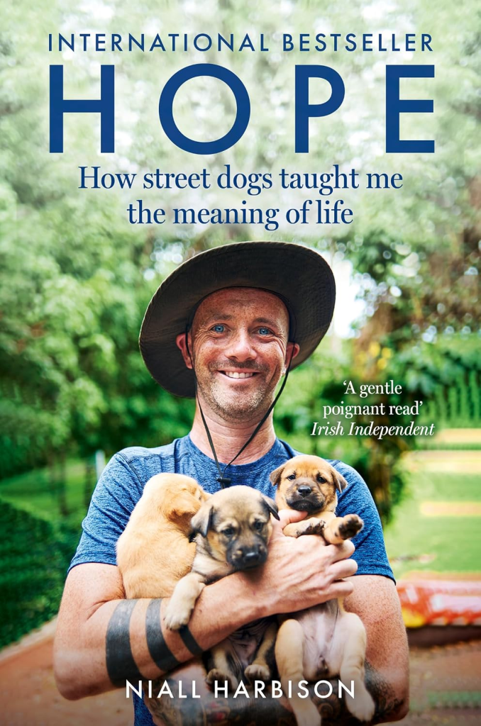 Book cover featuring a man with a hat holding three puppies, with the title 'HOPE' and subtitle about street dogs teaching life lessons.