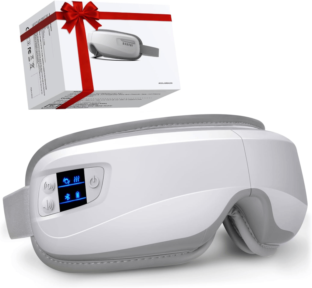 A white eye massager with a gray strap, featuring buttons and a digital display, alongside a gift-wrapped box.