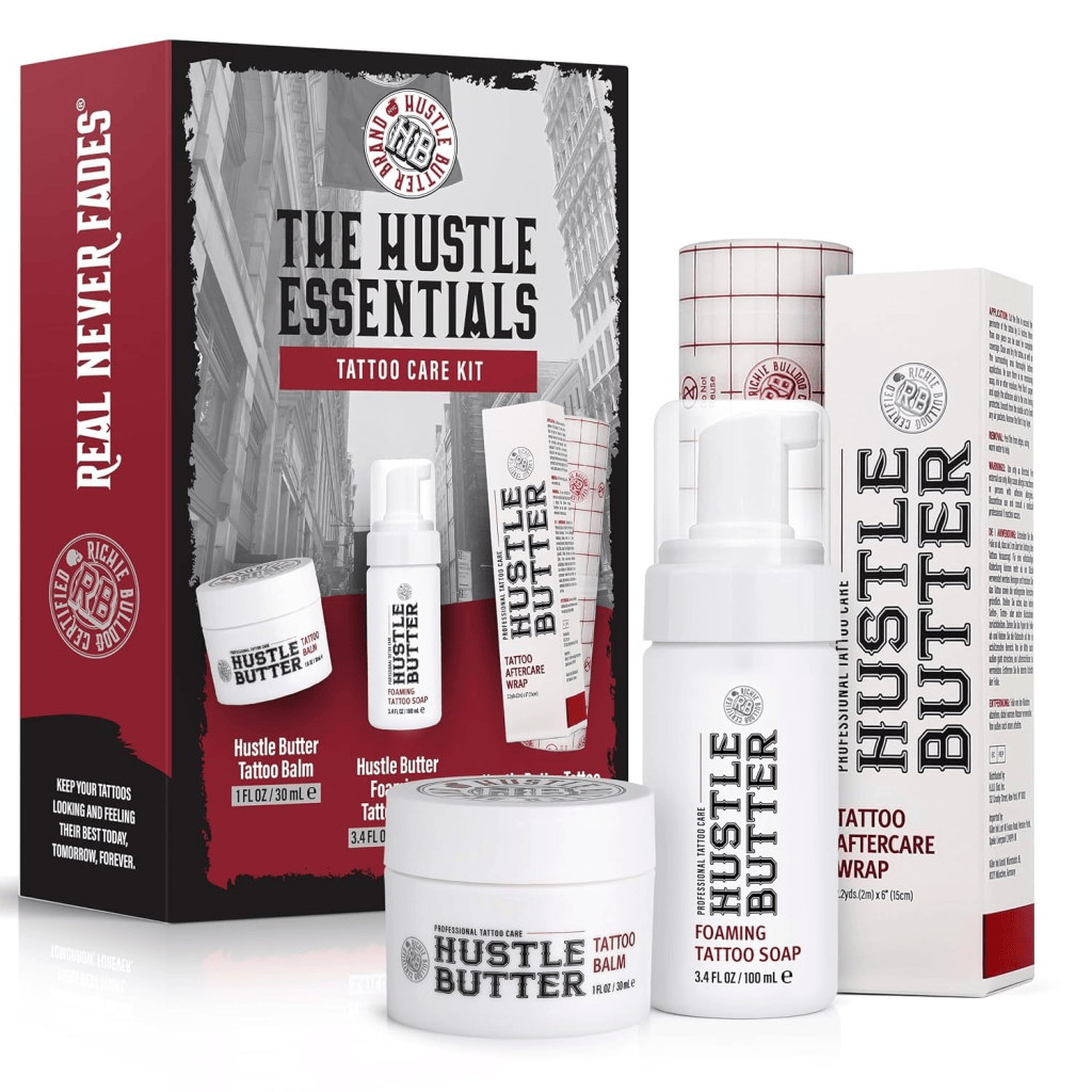 A tattoo care kit named 'The Hustle Essentials' featuring various products including Hustle Butter tattoo balm, foaming tattoo soap, and a tattoo aftercare wrap, all displayed in a decorative box.